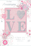 The anniversary card shown in the image has a gentle, romantic design that feels much like a carefully composed bouquet delivered to Old Oak Common homes. At its heart is the word LOVE, presented in bold, raised letters that can be clearly felt, each one trimmed with a fine coating of soft silver glitter. The effect is luminous but understated, catching the light like the faint glimmer on glass vases in a quiet living room. This central word sits upon a blush pink rectangle, framed by a larger field of pale pastel pink that blends seamlessly into the edges of the card. Around the lettering, a graceful display of illustrated flowers and leaves sweeps outward, their shapes delicate and slightly stylised, as though captured from a florist's sketchbook. Blossoms in blush pink, mauve, and pearly white mingle with soft grey outlines and silver touches, echoing the tones of romantic arrangements often chosen for anniversaries. The flowers' fine lines and gentle shading create depth without harsh contrast, reminiscent of the soft light that falls in the early evening across Old Oak Common's green spaces and nearby streets. Tiny decorative flourishes-petals, swirling tendrils, and almost-hidden butterflies-thread through the design, adding a sense of movement and quiet joy. Elegant script on the card conveys heartfelt anniversary wishes and enduring devotion, harmonising with the refined artwork. The overall impression is one of warmth, tenderness, and understated celebration, making this card an ideal partner to a hand-delivered arrangement from Flowers Old Oak Common, arriving at a doorstep near the canal or tucked into a cosy flat off Old Oak Common Lane.